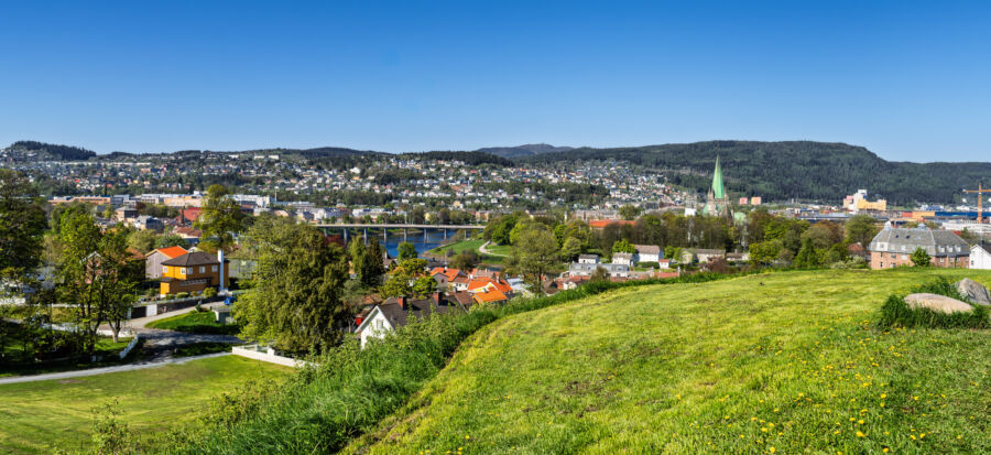 Scenic view of Trondheim, Norway, showcasing a charming seaside town surrounded by vibrant spring greenery.