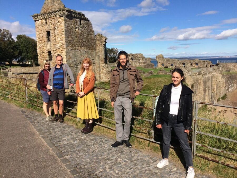 Tour participants gather in front of a castle as part of the St. Andrews Guided Walking Tour.