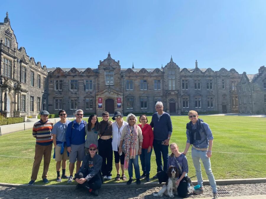 Group of people smiling and posing for a photo in front of a historic building during the St. Andrews Town Guided Walking Tour.