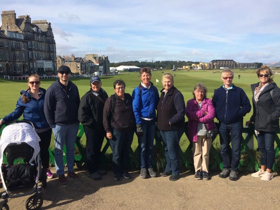 Participants of the St. Andrews Town Guided Walking Tour gather in front of a green fence.