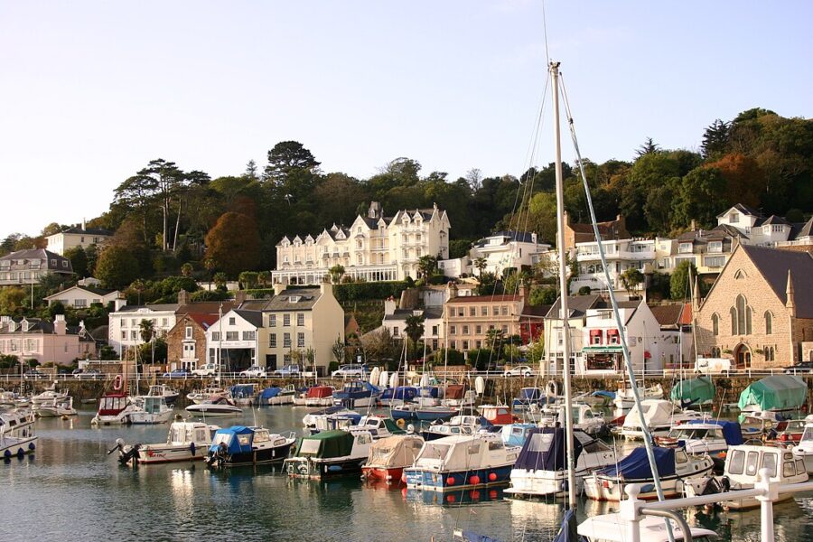 St. Aubin harbor bustling with various boats moored at the docks under a clear sky.