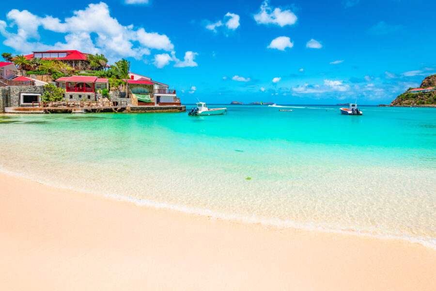 Tranquil St. Barts beach featuring golden sand and the sparkling Caribbean Sea under a clear sky.