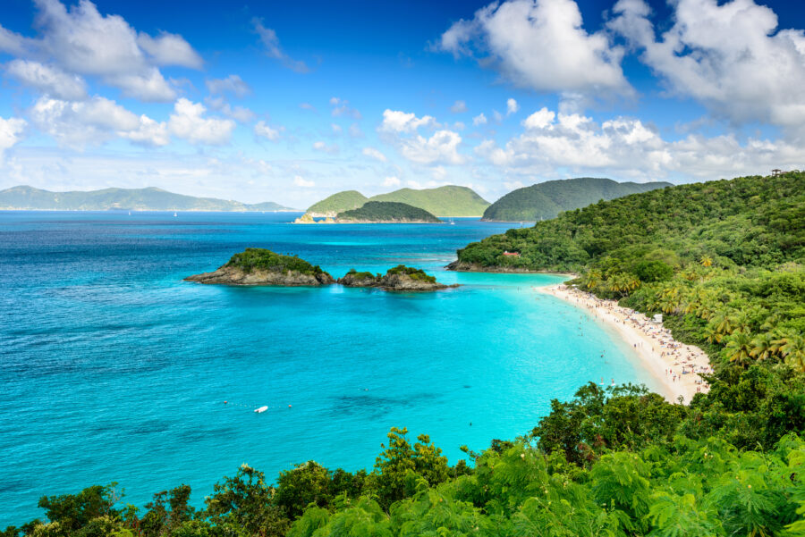 Scenic view of Trunk Bay, St. John, USVI, featuring white sandy beach, vibrant blue water, and surrounding tropical foliage.