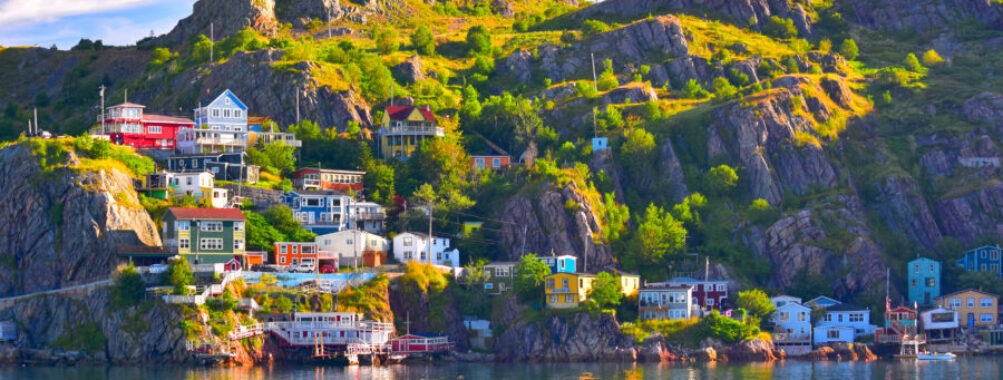 Panoramic view of The Battery community overlooking St. John's Harbour in Newfoundland, Canada, showcasing colorful houses and water.