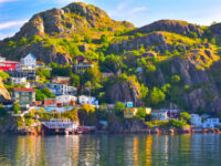Panoramic view of The Battery community overlooking St. John's Harbour in Newfoundland, Canada, showcasing colorful houses and water.
