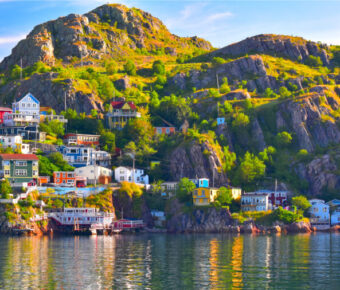 Panoramic view of The Battery community overlooking St. John's Harbour in Newfoundland, Canada, showcasing colorful houses and water.
