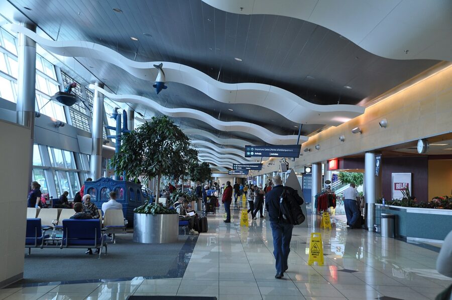 People walking through St. John’s International Airport terminal, carrying luggage and navigating the busy space.