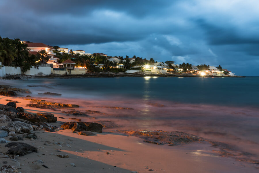 Serene night view of St. Maarten, illuminated by colorful lights reflecting on the water