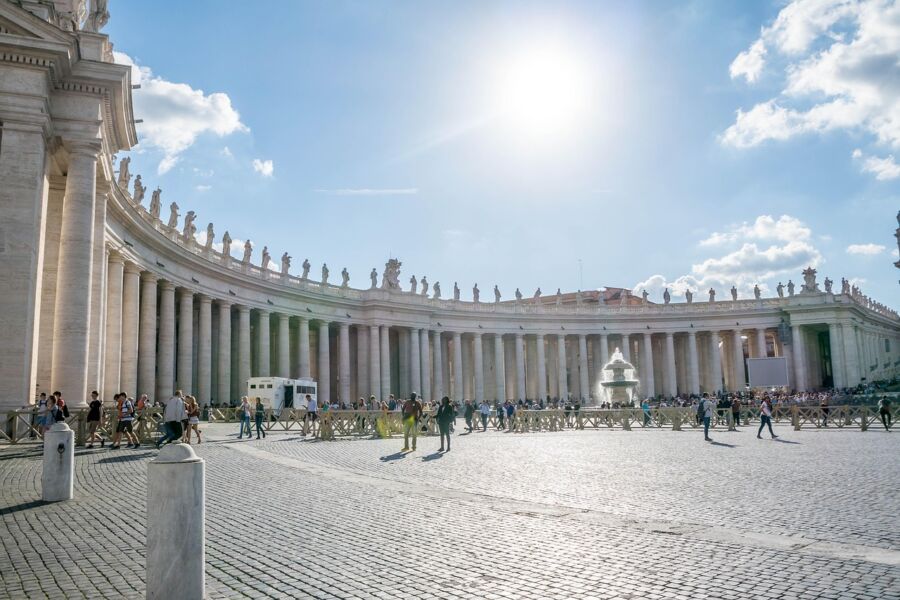Vibrant St. Peters Square in Vatican City; sunny day highlights historic architecture and diverse visitors.