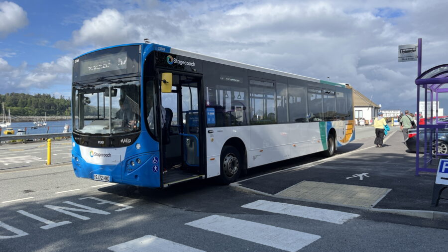 Stagecoach bus parked by scenic coastal area, highlighting transportation and picturesque harbor views.