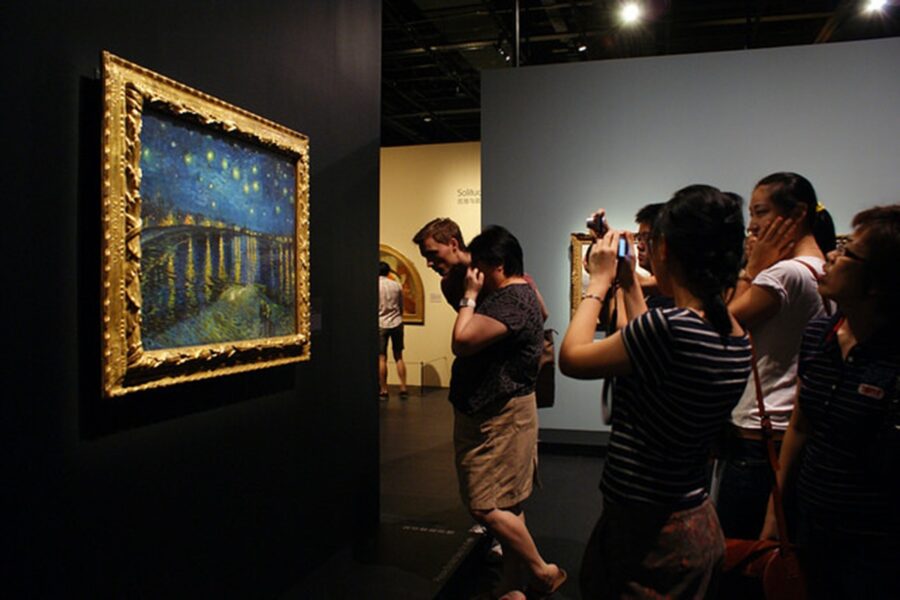 Visitors admiring Van Gogh-inspired painting in vibrant art gallery setting.