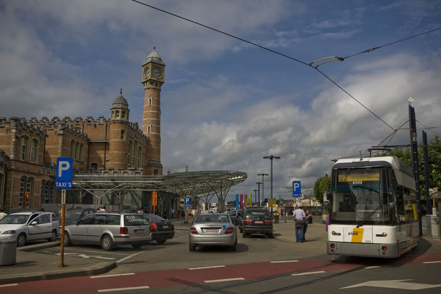 Bus navigates a street flanked by parked cars, illustrating the busy environment of urban transit.