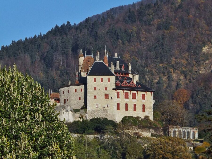 Château de Menthon-Saint-Bernard: stone castle with turrets, slate roof and terraced gardens on forested hillside.