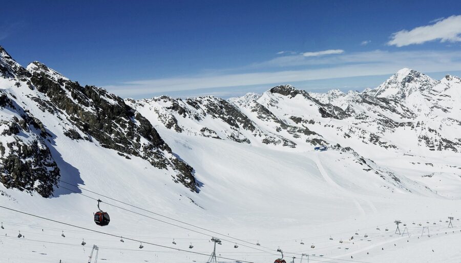 Ski lift ascending through snowy landscape at Stubai Glacier, Austria, surrounded by majestic mountains.