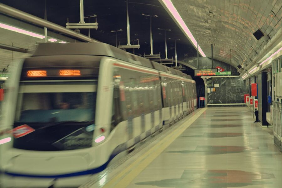 Modern subway station with sleek white train in motion amidst polished architectural elements.