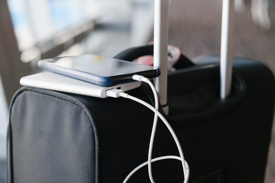 Modern black suitcase with smartphone, charger, and cables in an airport setting.