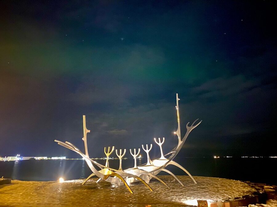 The Sun Voyager sculpture in Reykjavik, Iceland, depicted under the colorful lights of the Aurora Borealis.