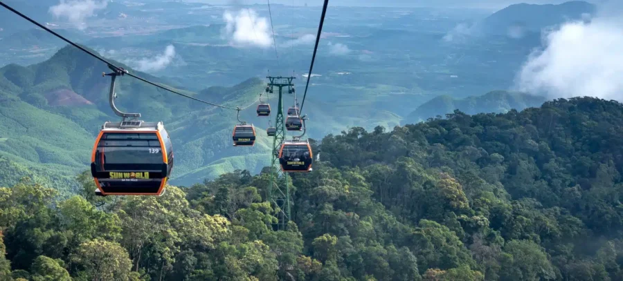 Sun World Ba Na Hills cable car gliding over lush Vietnam mountain forest landscape.