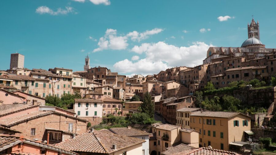 Siena, Tuscany, Italy sunlit terracotta rooftops and domed cathedral skyline.