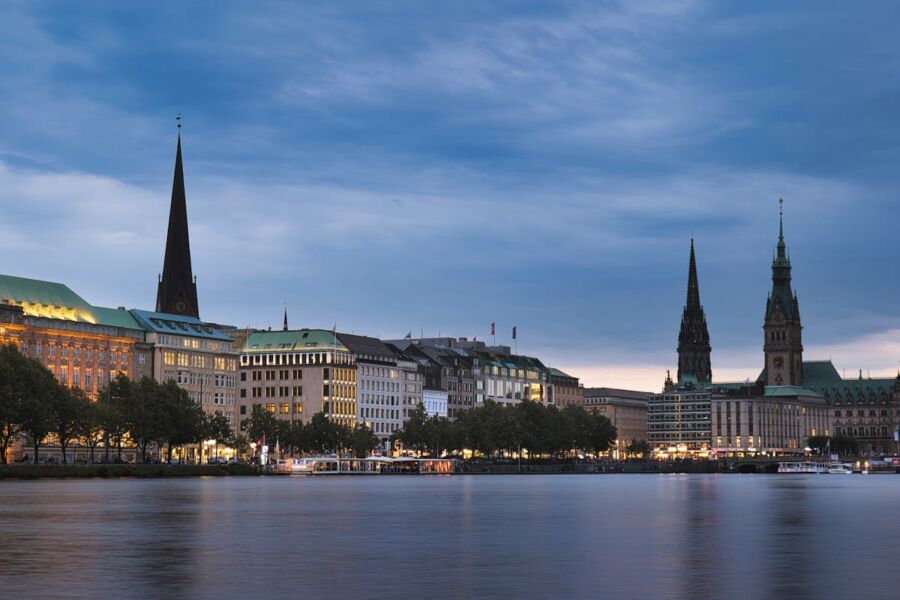 Twilight waterfront scene in Hamburg with historic architecture, reflecting sky, and leisure boats.