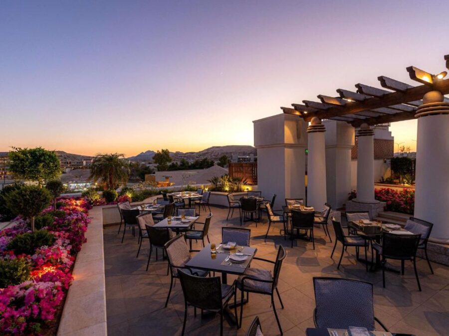 Romantic sunset terrace restaurant with mountain view at luxury Petra resort, outdoor dining tables.