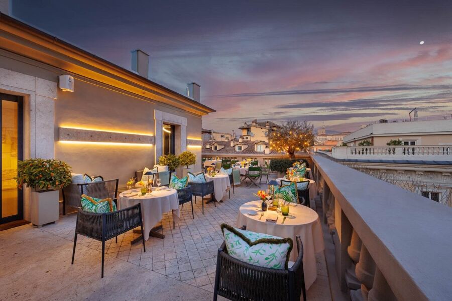 Rooftop terrace restaurant with sunset, elegant tables, and a stunning urban skyline view.