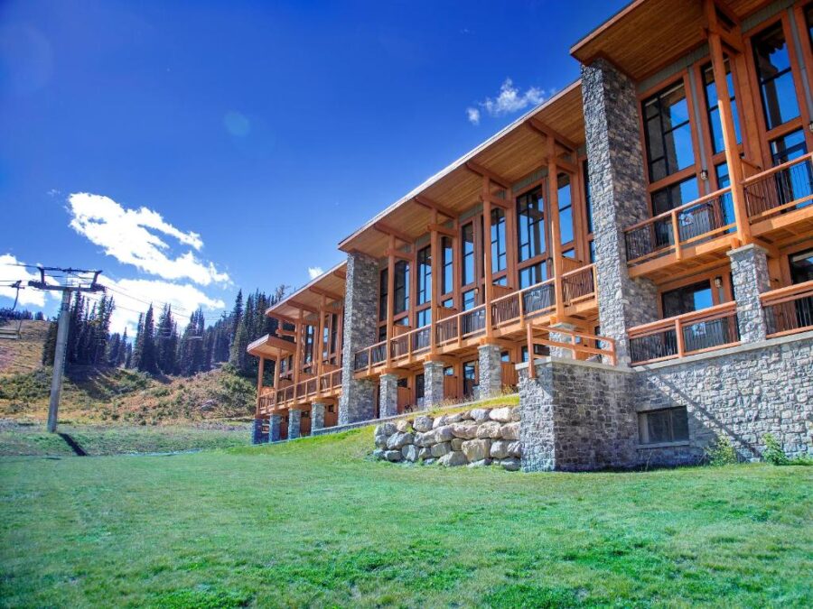 Sunshine Mountain Lodge at the summit of Whistler, surrounded by snow-capped peaks and clear blue skies in Banff, Canada.