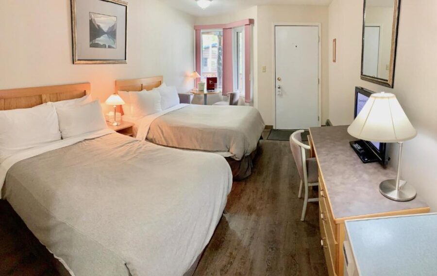Two beds in a cozy room with a television at Sunwapta Falls Rocky Mountain Lodge, Canada.
