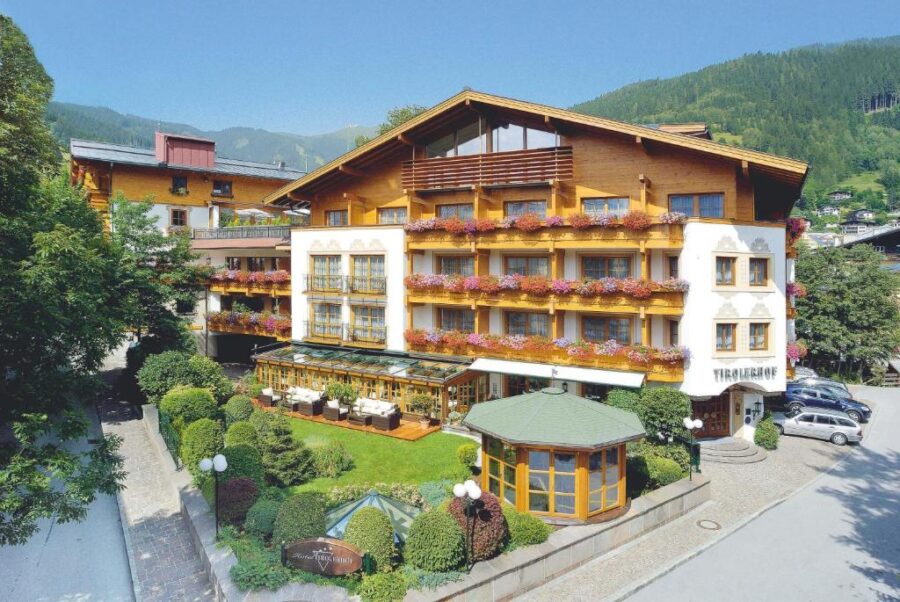 The Superior Hotel Tirolerhof Zell am See, surrounded by vibrant trees and stunning mountain views.