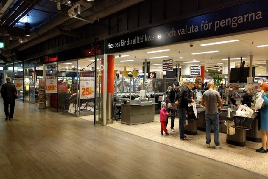 Uppsala supermarket entrance with checkout lanes and shoppers.