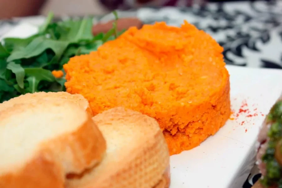 Almogrote sweet potato mash with toasted crostini and arugula, paprika-seasoned appetizer.