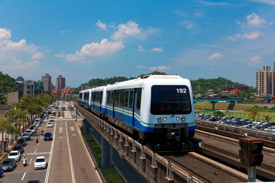 Elevated Taipei Metro train traveling through a suburban area, showcasing the urban landscape below