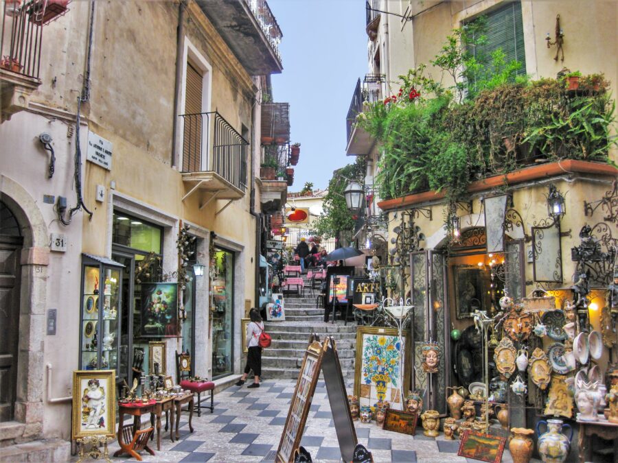 Picturesque street in Taormina, Italy, featuring colorful facades and medieval architecture under a clear blue sky