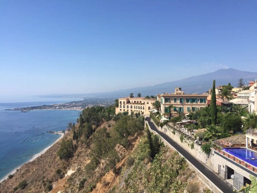 Scenic view from a hilltop in Taormina, Italy, showcasing the expansive ocean and coastal landscape below.