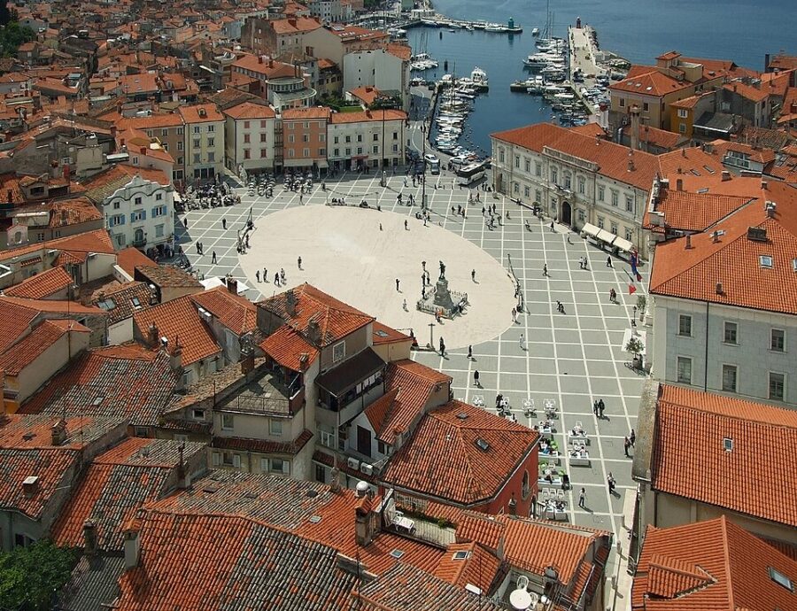 Aerial view of Piran's Tartini Square, showcasing red roofs and a picturesque harbor.