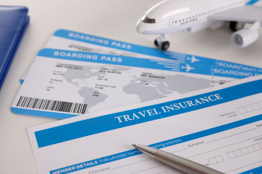 Airplane tickets and an empty travel insurance form with a pen, ready for information to be filled in