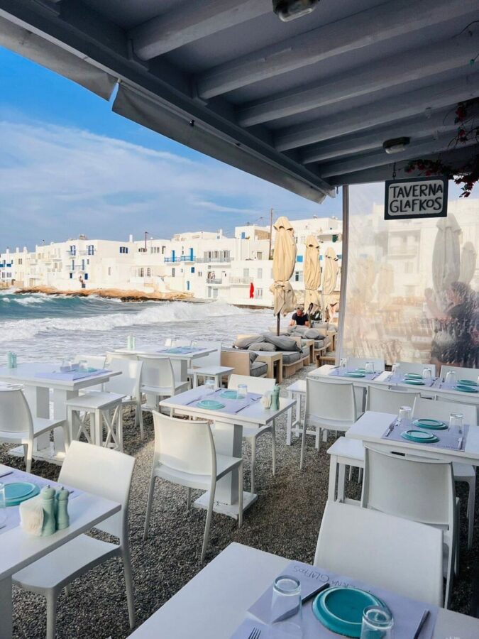 Taverna Glafkos on the beach, showcasing white tables and chairs, inviting diners to enjoy the seaside view in Paros, Greece.