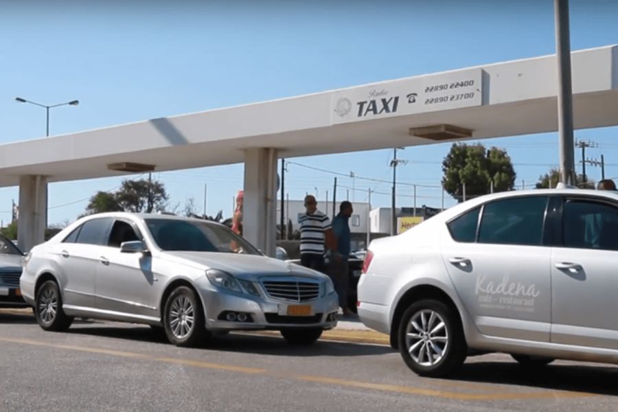 Taxi stand in urban Mykonos with Mercedes-Benz and local service vehicles.