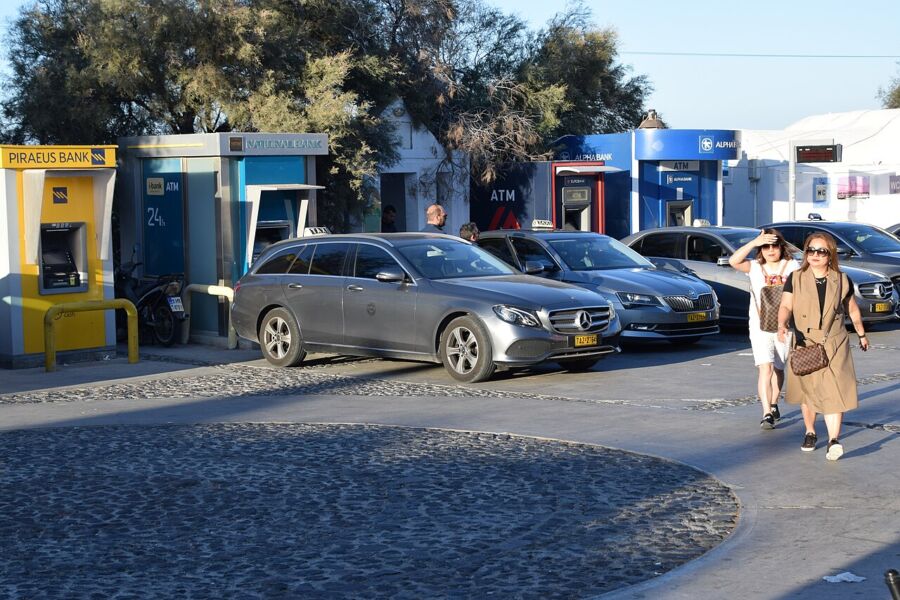 Taxis lined up on a street in Santorini, showcasing the island's unique architecture and vibrant atmosphere.