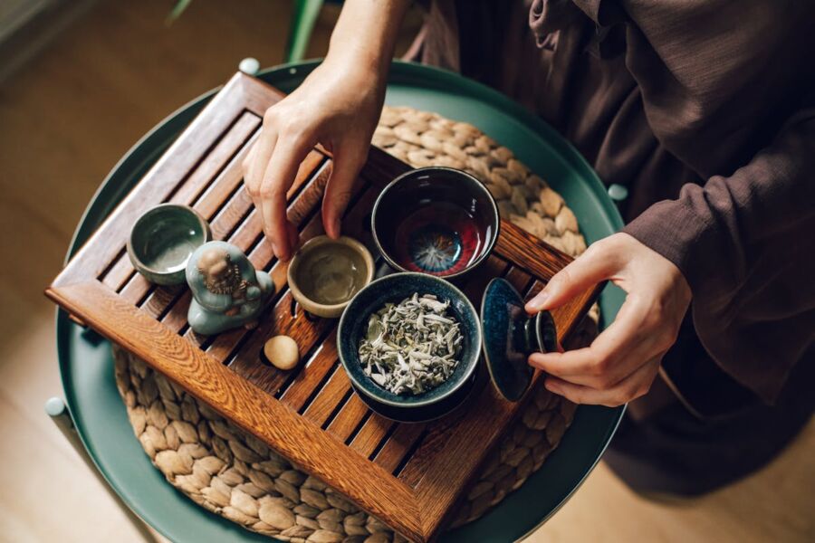 Serene tea ritual with diverse bowls, wooden tray, and spiritual figurine enhancing peaceful ambiance.