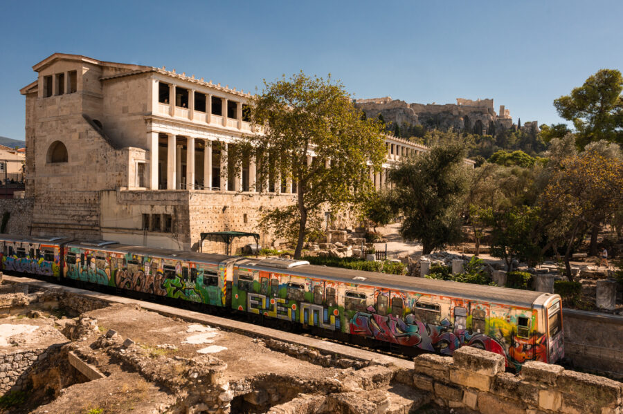 Graffiti on Metro Line 1 in Athens contrasts modern expression with the historic backdrop of the Acropolis and Temple of Hephaestus
