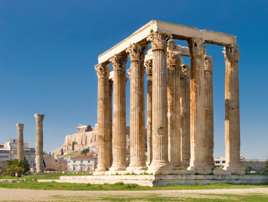 The Temple of Olympian Zeus in Athens, Greece, featuring towering columns and ancient ruins against a clear blue sky