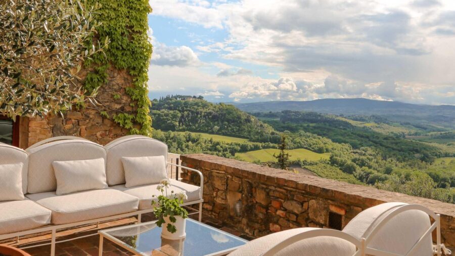 Serene outdoor terrace with modern seating, stone wall, and countryside view.
