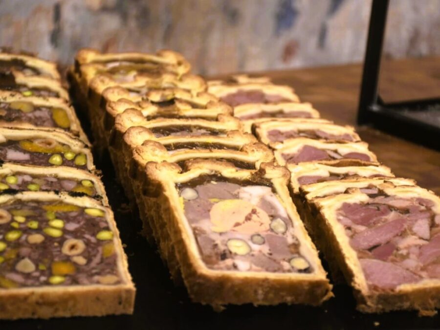 Pâté de Reims terrine slices in flaky pastry with pistachios, charcuterie display.