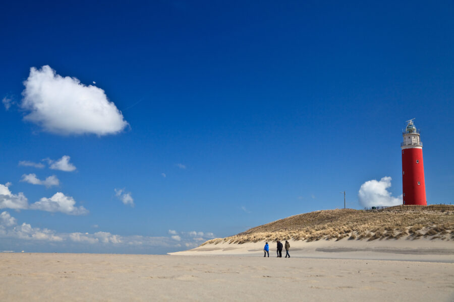 Lighthouse standing tall amidst the sandy dunes on Texel Island beach, surrounded by natural coastal scenery.