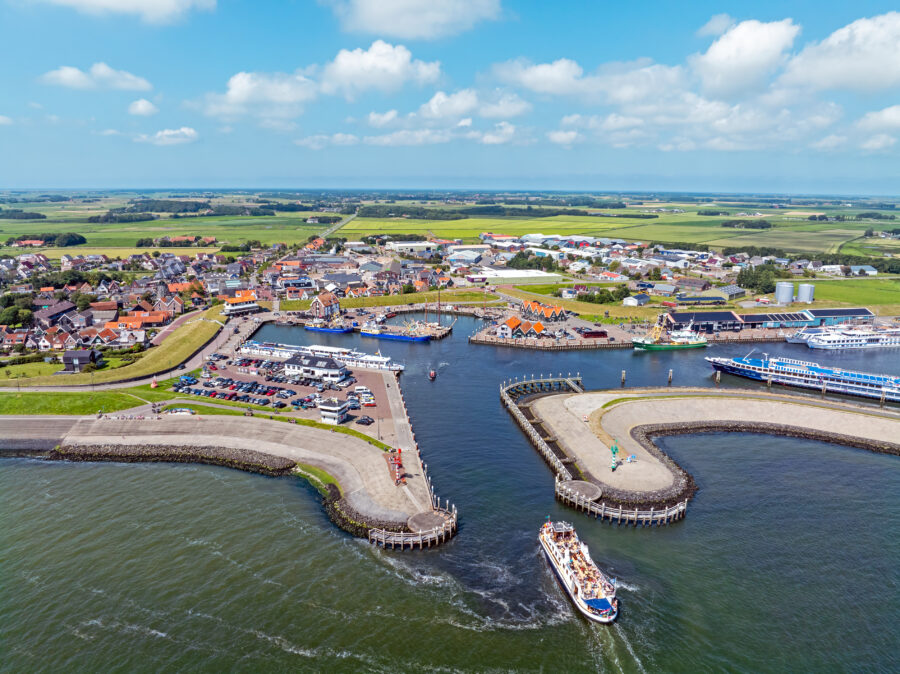 Aerial view of Oudeschild, showcasing the city and harbor on Texel Island, Netherlands, with water and boats visible.
