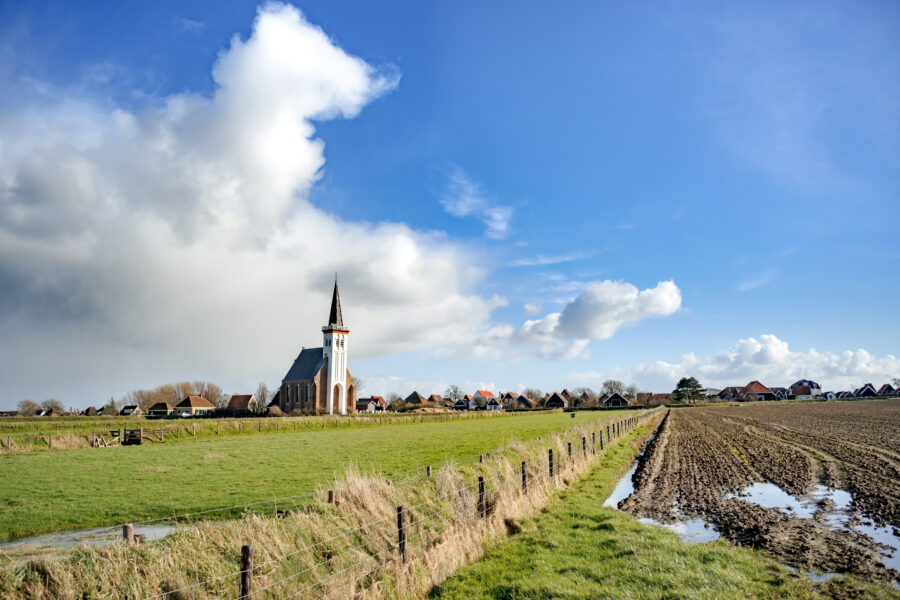 White church surrounded by lush landscape on Texel Island, Holland, showcasing the serene beauty of the area.