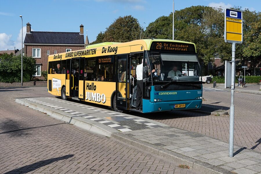 Texel, Netherlands bus stationed near lush greenery and charming Dutch-style houses.
