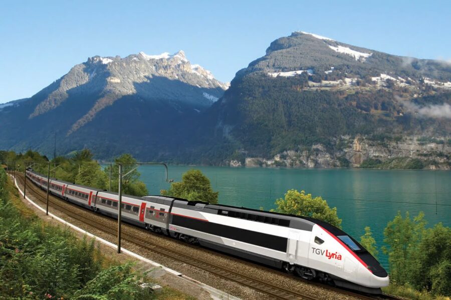 High-speed TGV Lyria train crosses scenic lakeside with mountains, blending nature and technology.