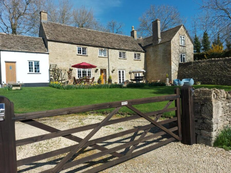 Thames Head Wharf's historic stone house with a charming gate and a lush green lawn surrounding it.